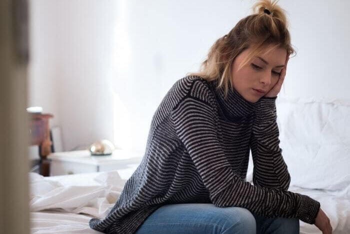 woman-sat-on-bed-looking-tired